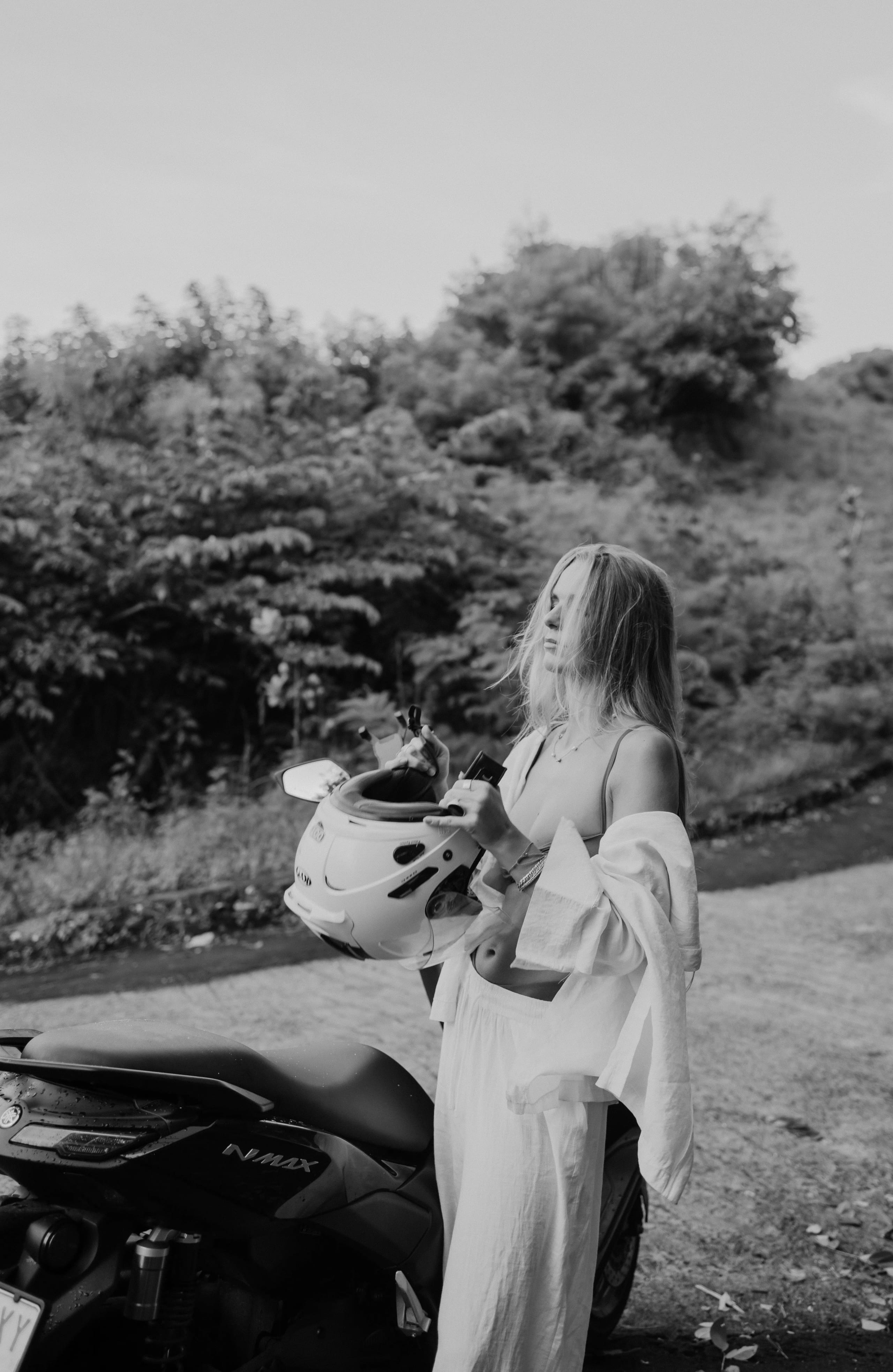Lies Zhara met een helm bij een scooter in de tropen, zwart-wit