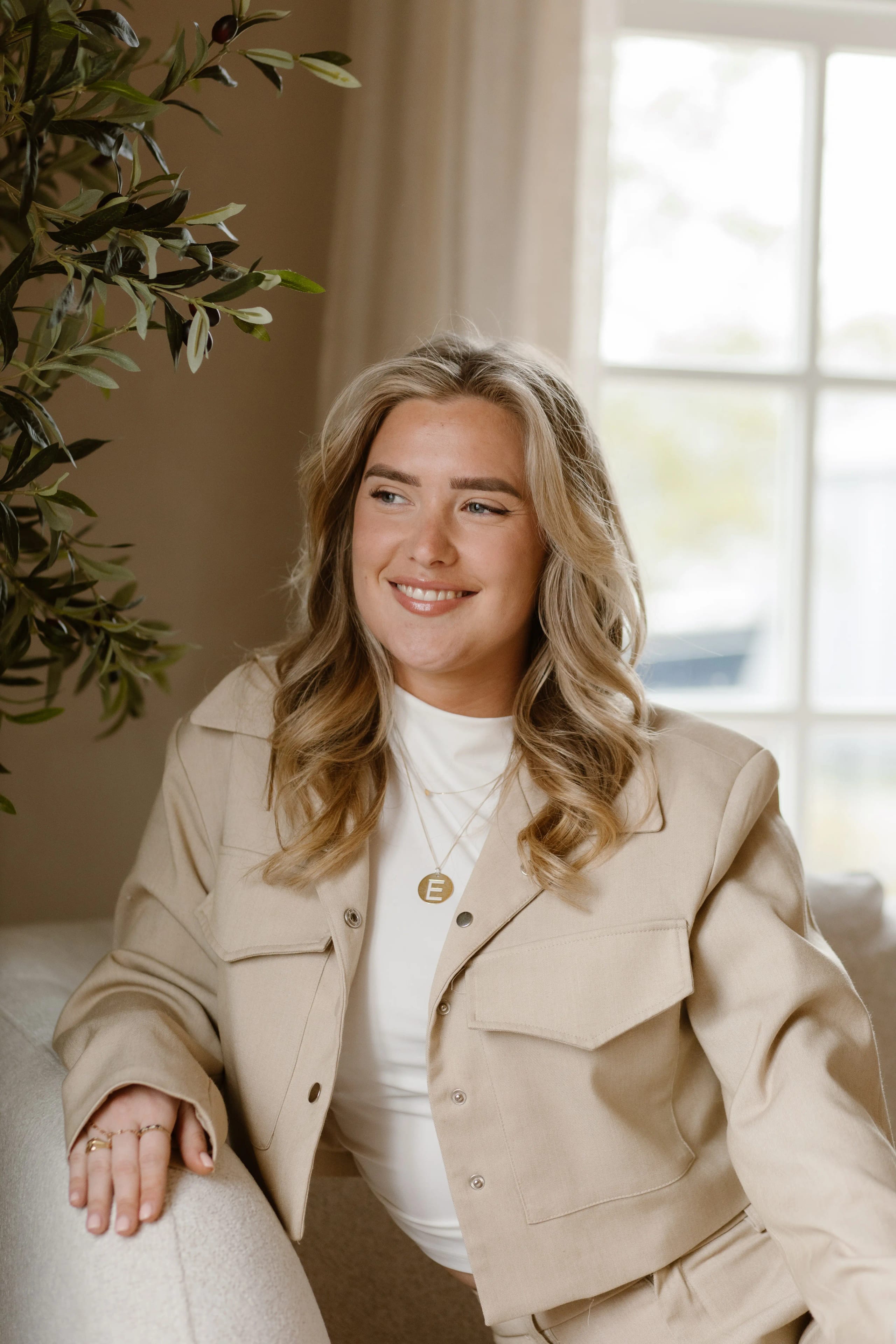 Elegante portretfoto van een vrouw met blond haar en een beige jas, merkfotografie voor Beauty By Cil in Hoofddorp