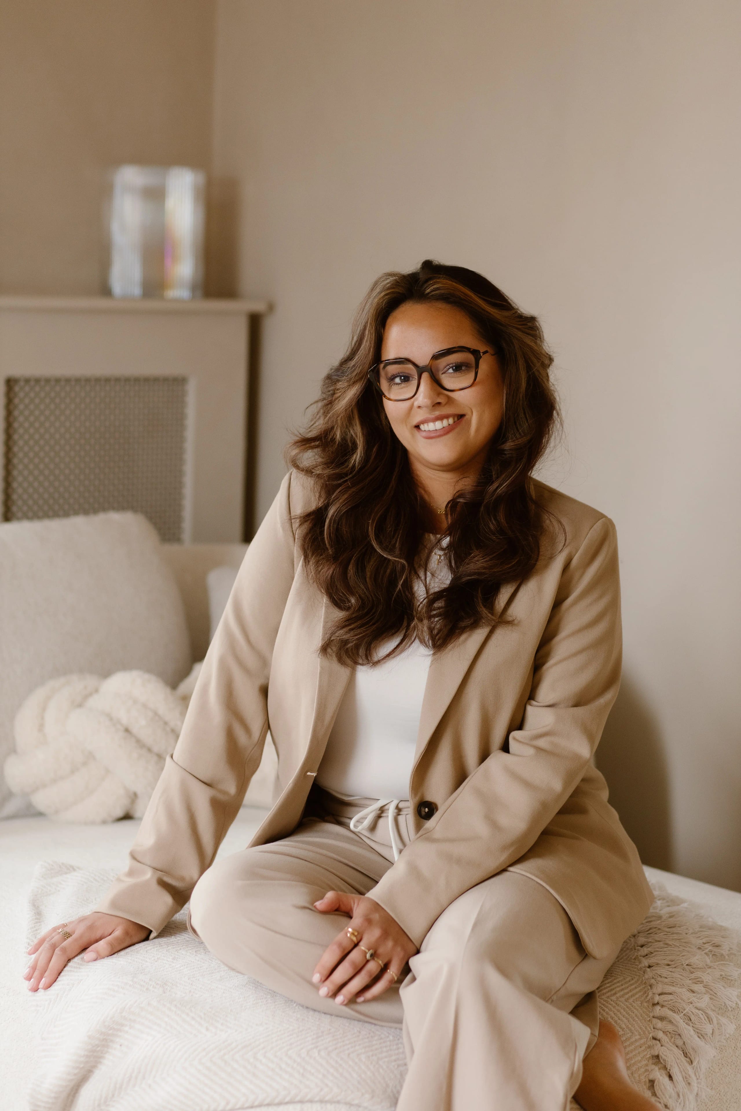 Twee vrouwen van het team Beauty By Cil zittend op een bed terwijl ze samen een tijdschrift lezen in een lichte studio