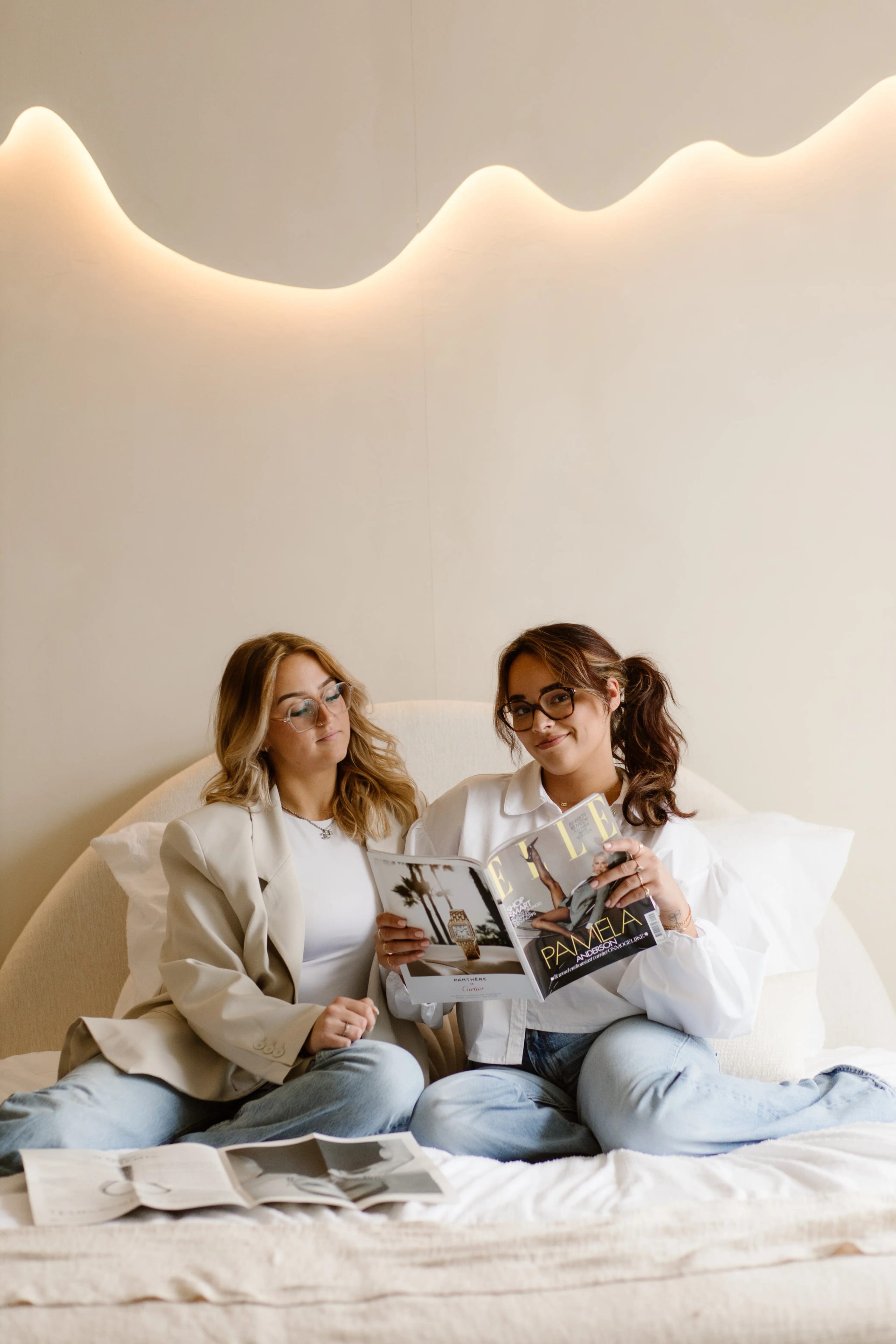 Portret van een brunette vrouw in een beige blazer die bij een raam staat, professionele brand portrait door Denise B Photography