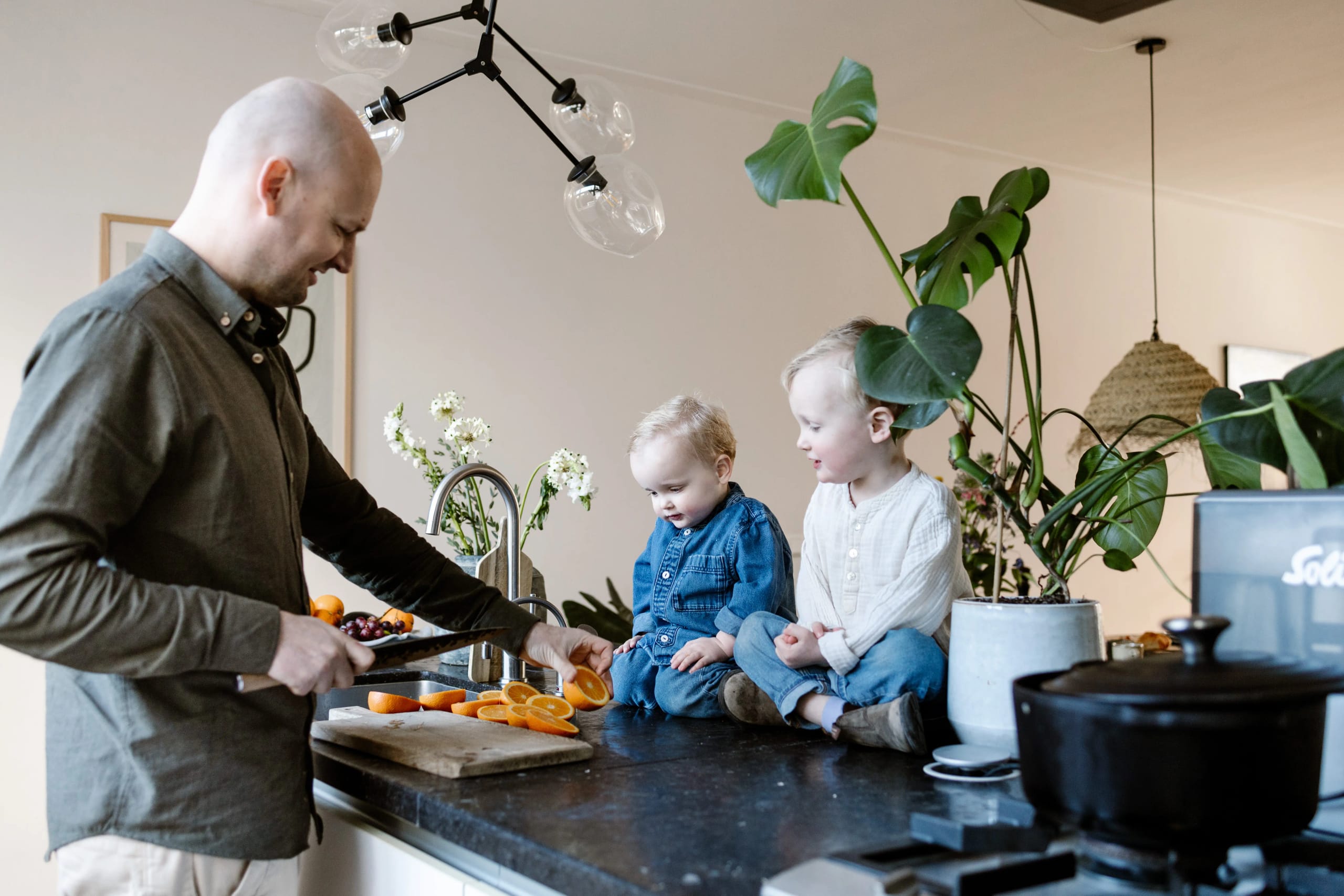 Vader en kinderen snijden sinaasappels tijdens een familie fotoshoot thuis in Hoofddorp door Denise B Photography.
