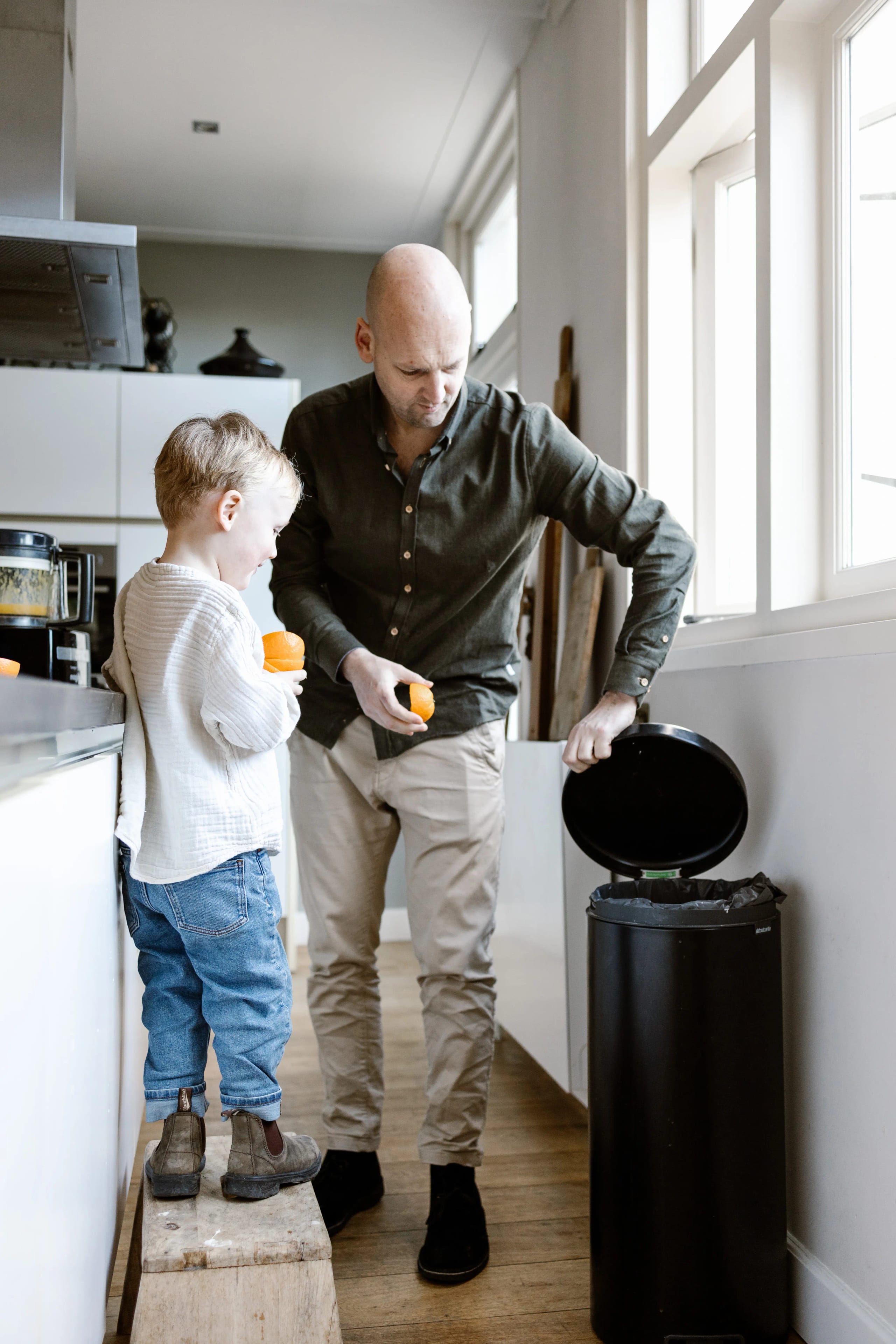 Natuurlijk moment tijdens een thuis shoot: vader ruimt op met hulp van zijn kinderen.