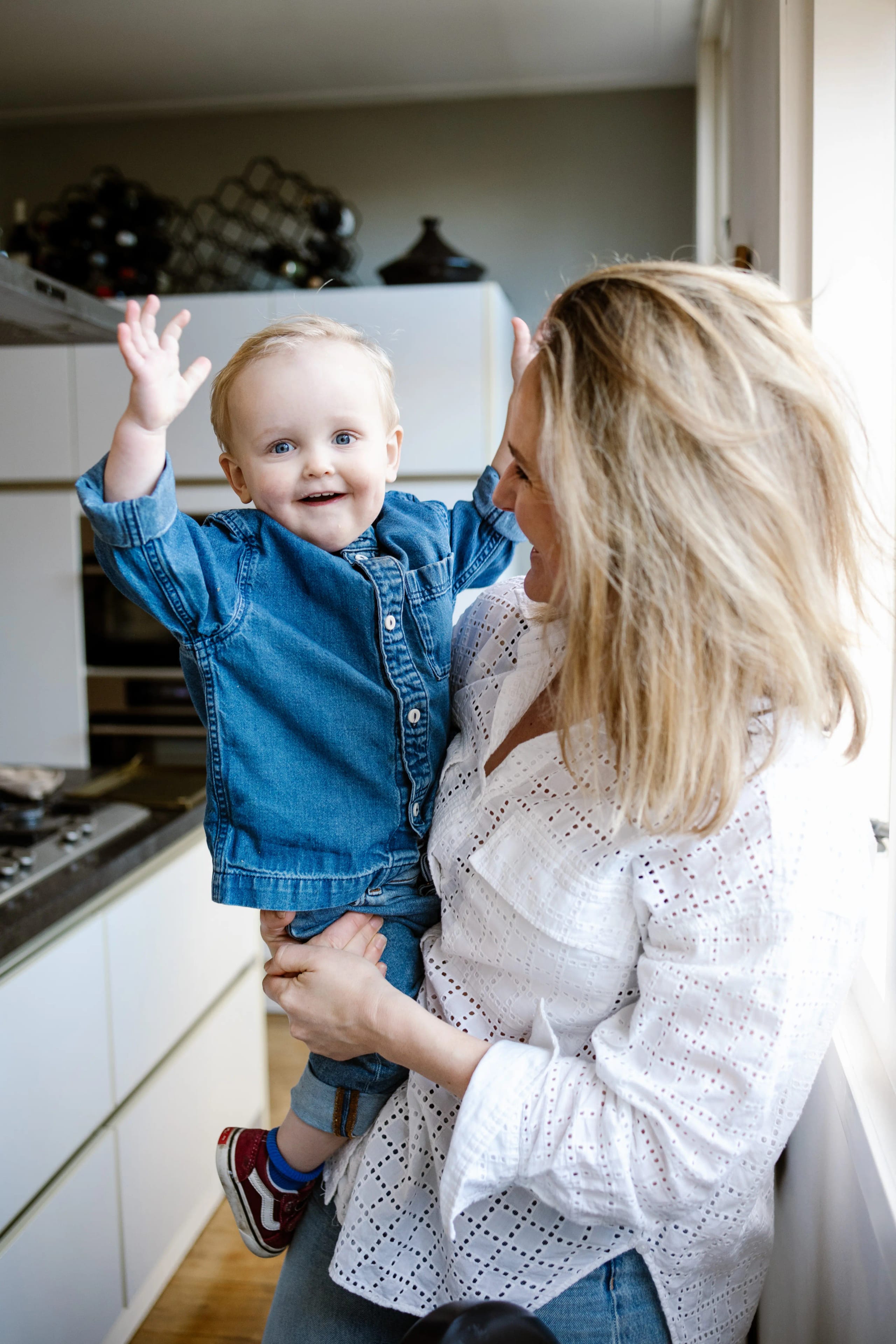 Liefdevol portret van een moeder die haar peuter vasthoudt tijdens een familie fotoshoot.