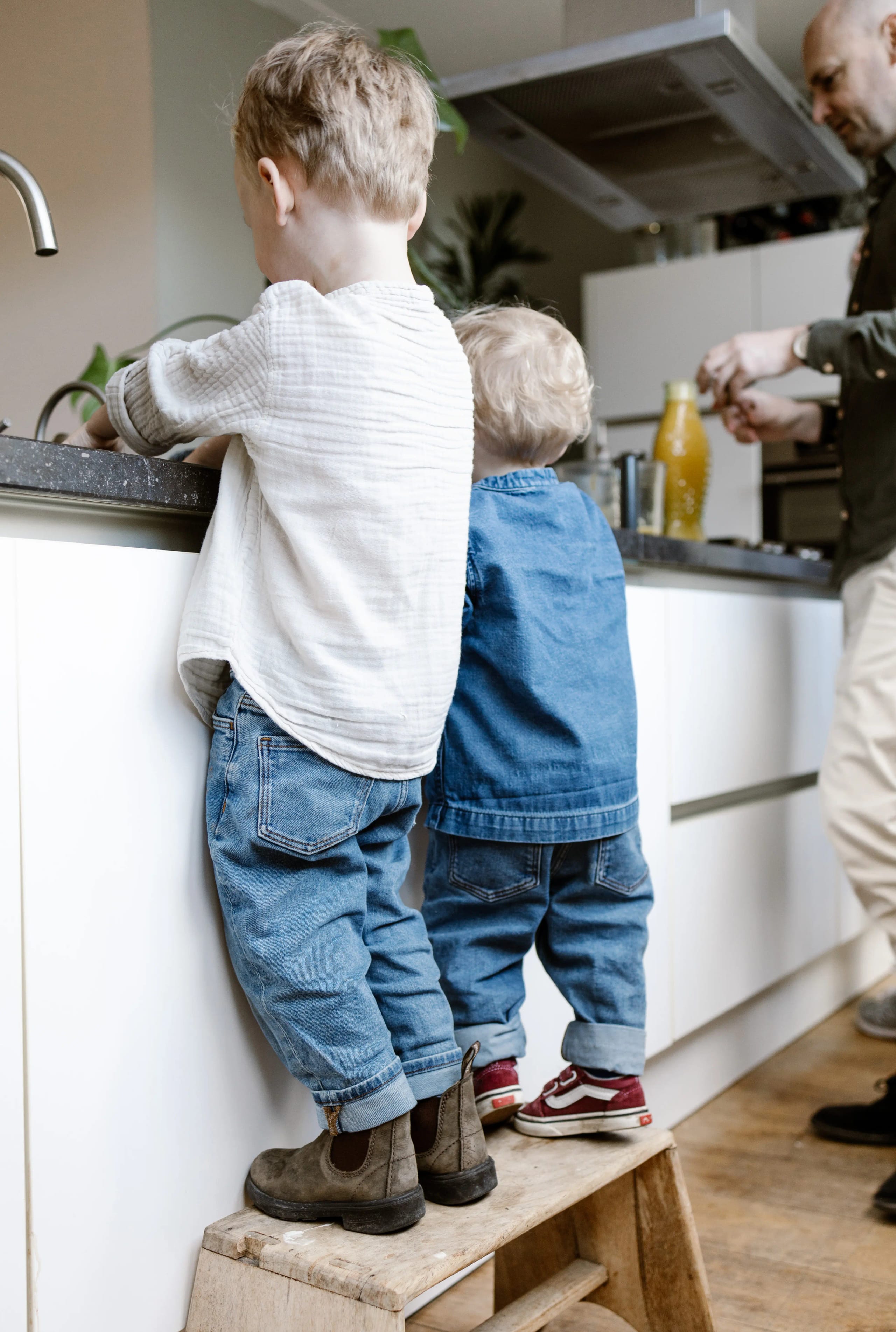 Twee broertjes staan samen aan het aanrecht in een lichte keuken, natuurlijke kinderfotografie.