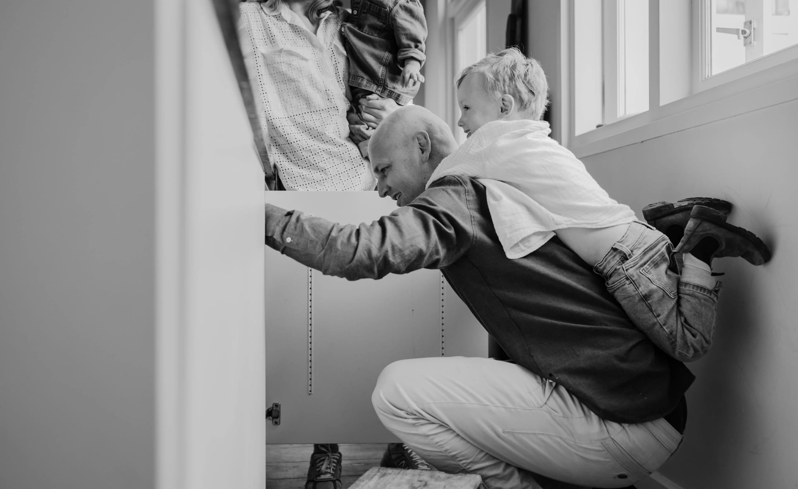 Zwart-wit moment van vader en zoon in de keuken, authentieke gezinsmomenten vastgelegd.