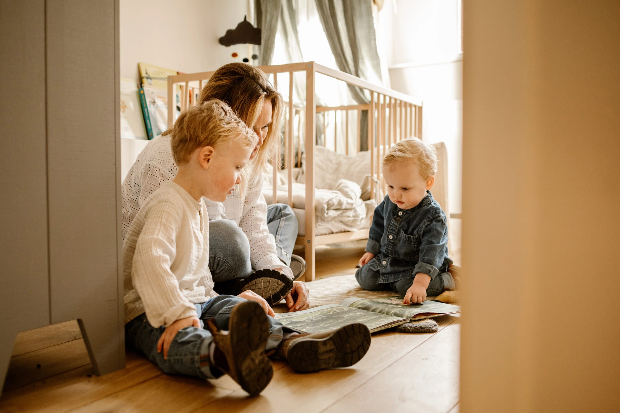 Moeder leest voor aan haar twee kinderen in de babykamer, intieme familieportretten.