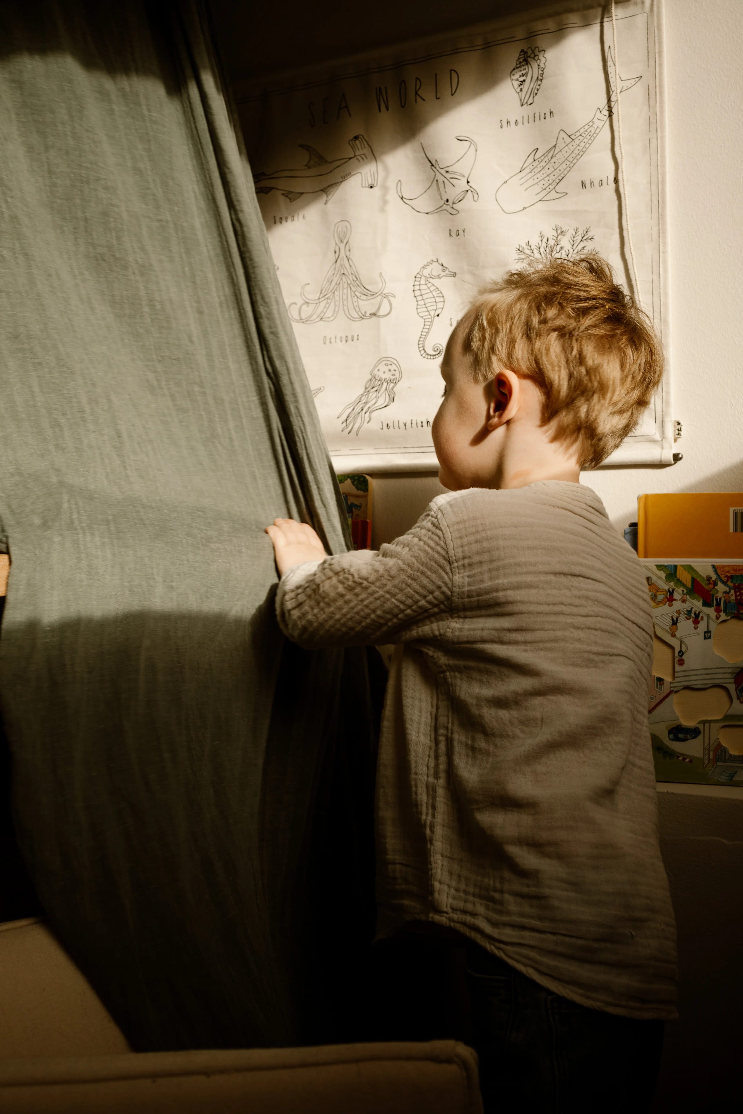 Peuter die verstoppertje speelt achter een gordijn, speelse thuis fotografie in Hoofddorp.