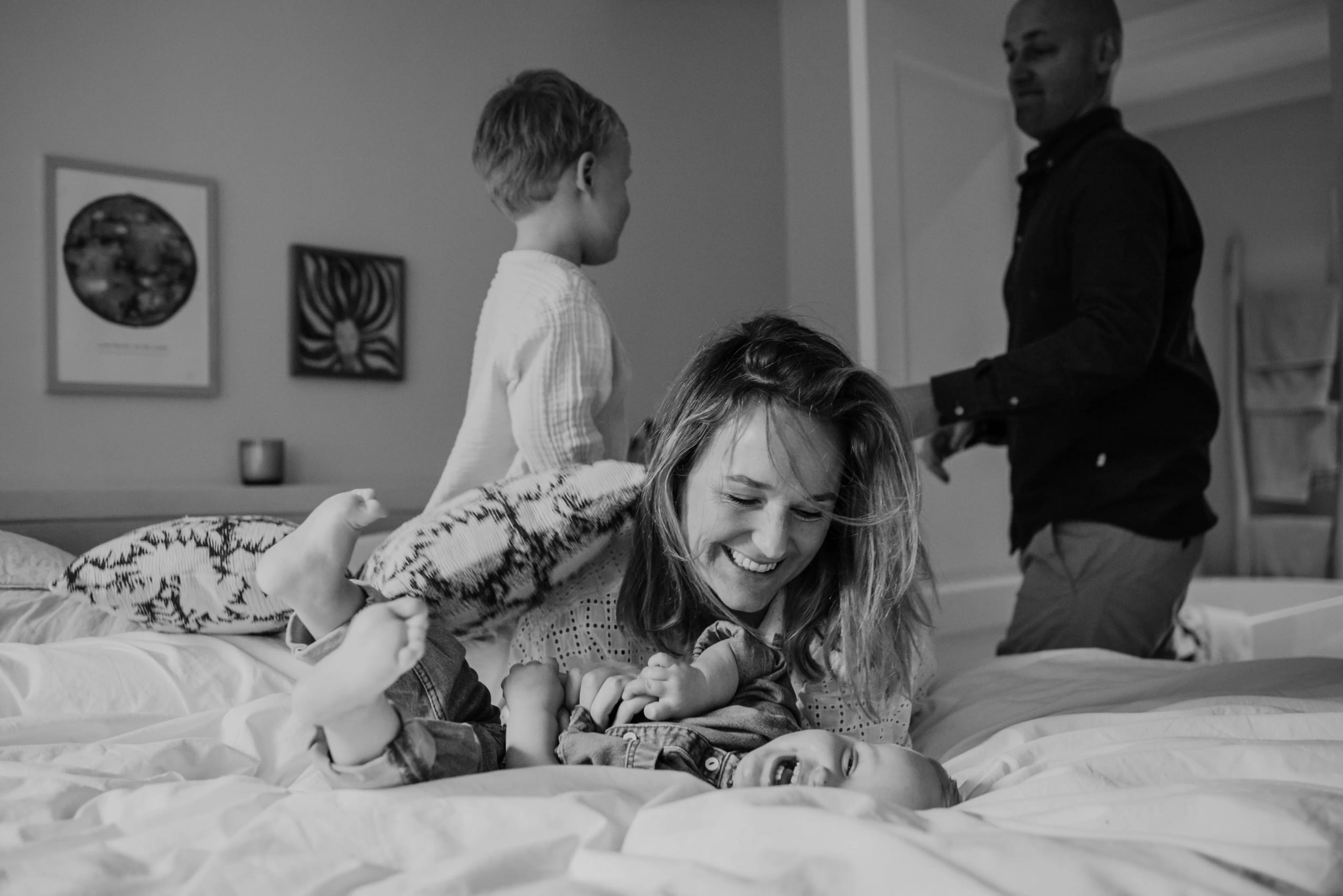 Lachende moeder met haar kind op bed, zwart-wit lifestyle fotografie door Denise B Photography.