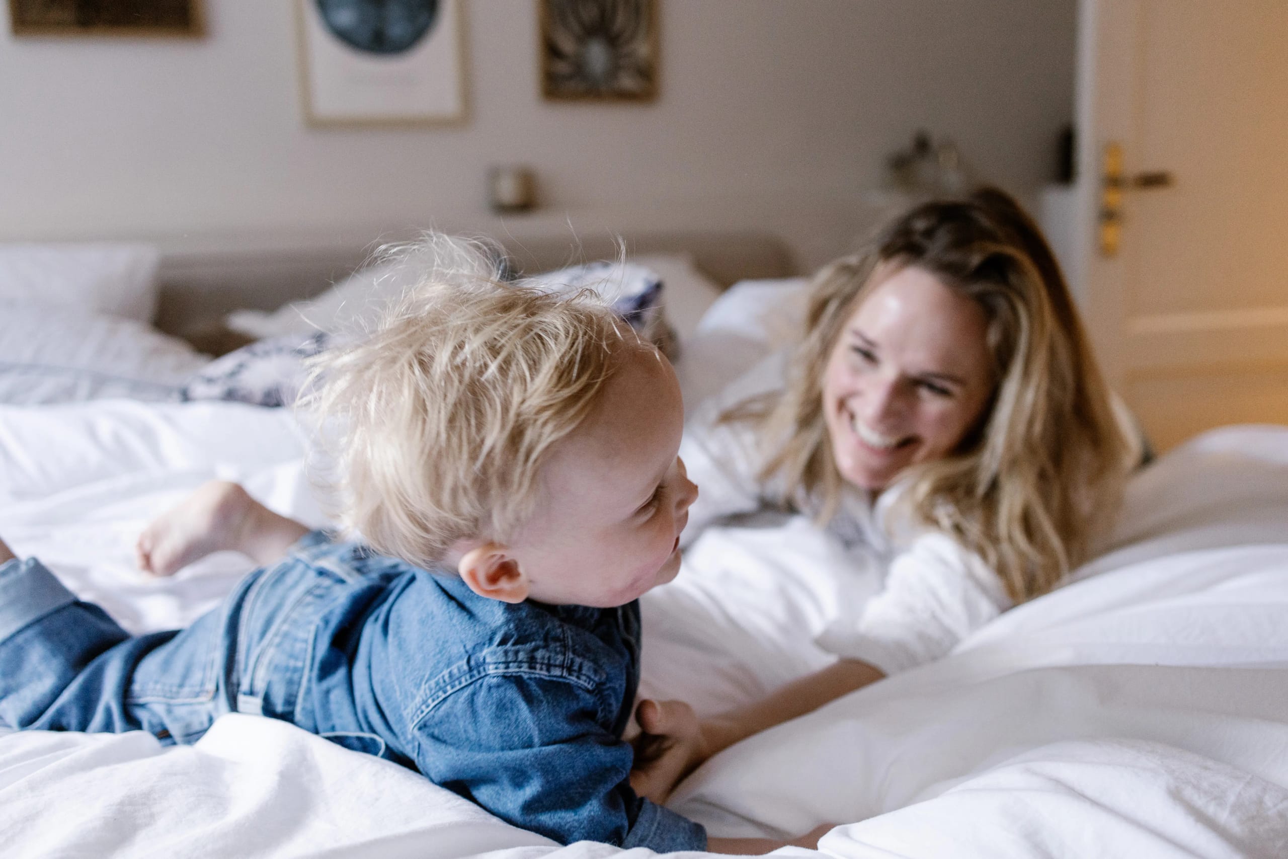 Gezellig moment op bed met moeder en kind, warme en natuurlijke familiefotografie.