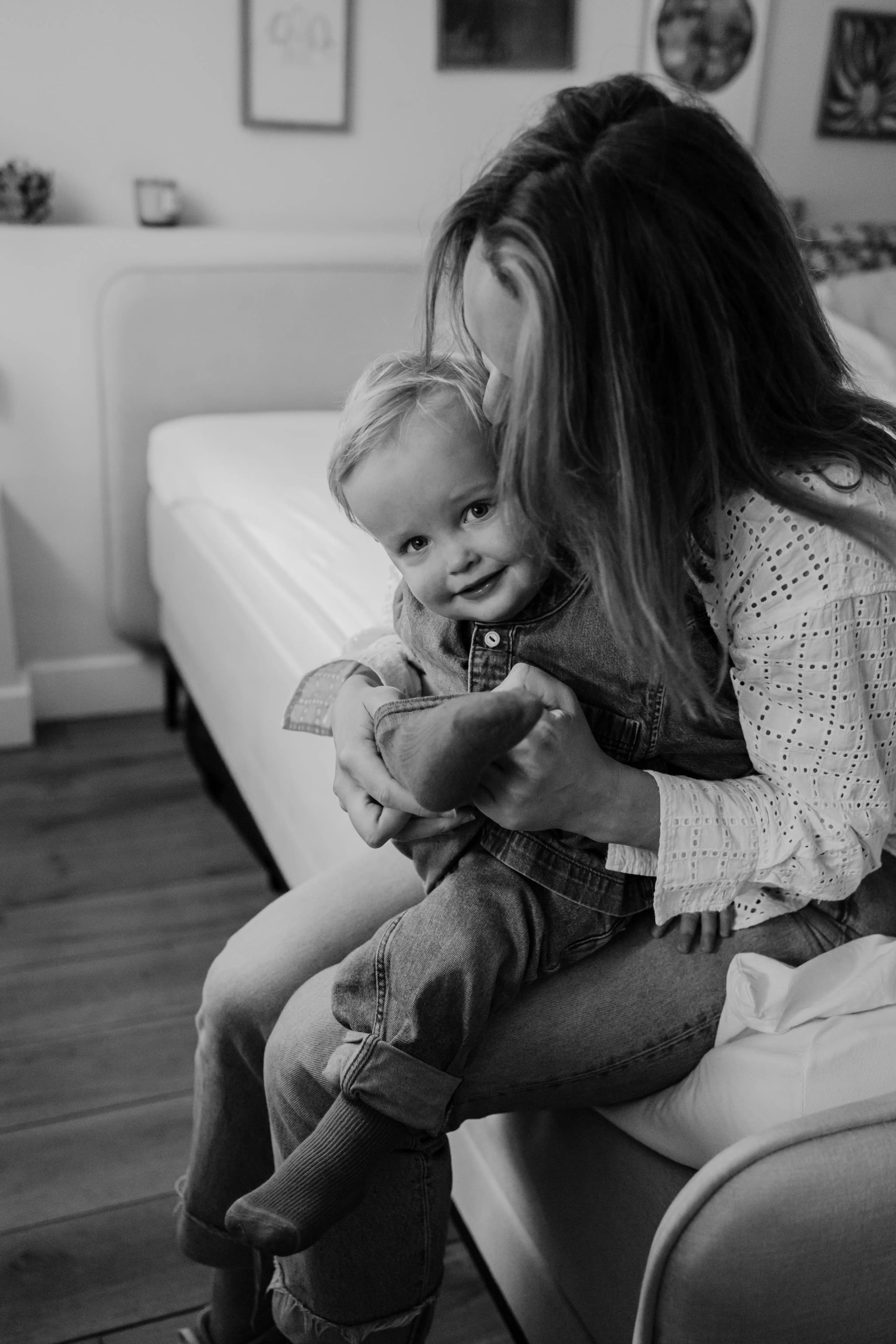 Moeder knuffelt met haar kind in de slaapkamer, zwart-wit lifestyle portret.