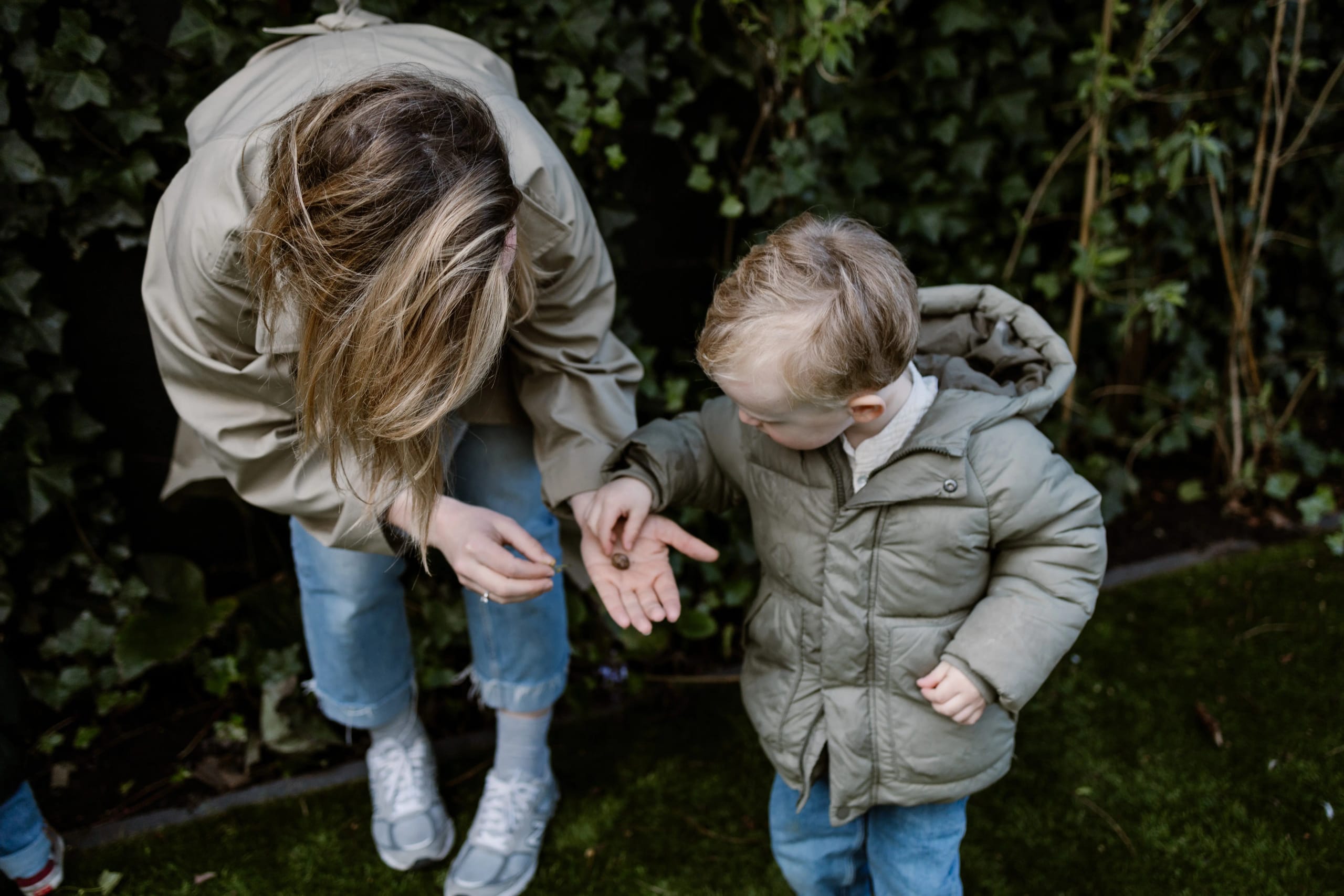 Moeder en kind ontdekken de natuur in hun eigen tuin tijdens een fotoshoot.