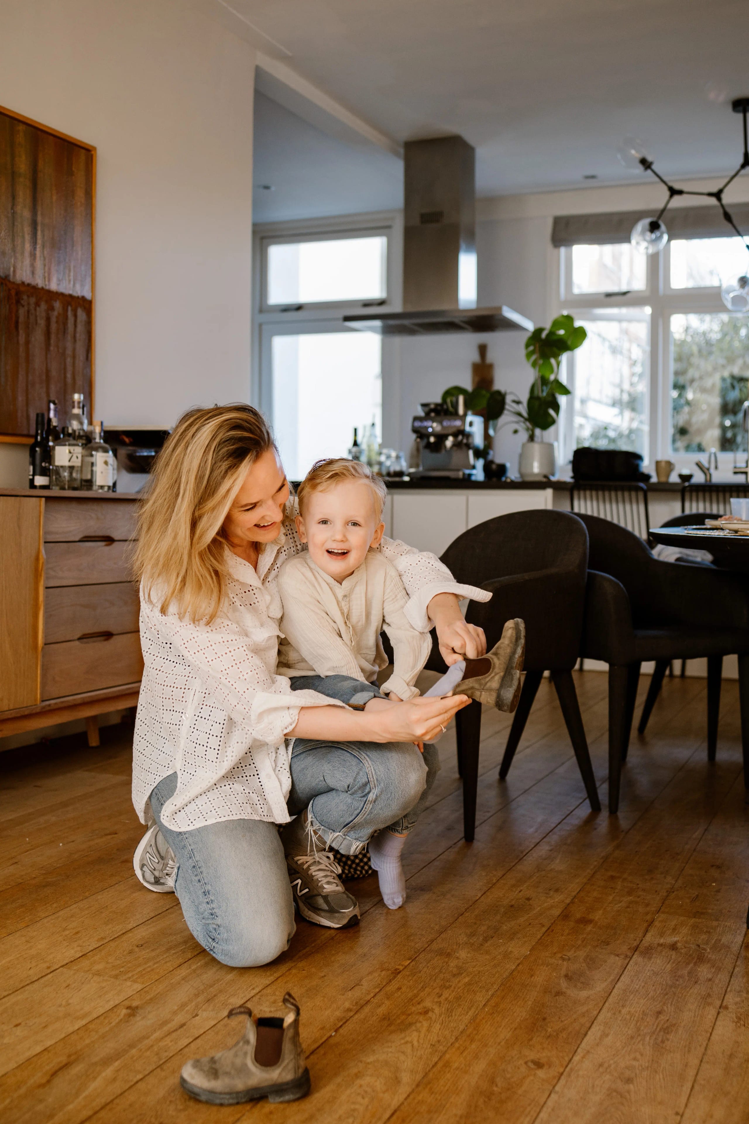 Moeder houdt haar kind vast in een modern interieur, lifestyle fotografie aan huis.