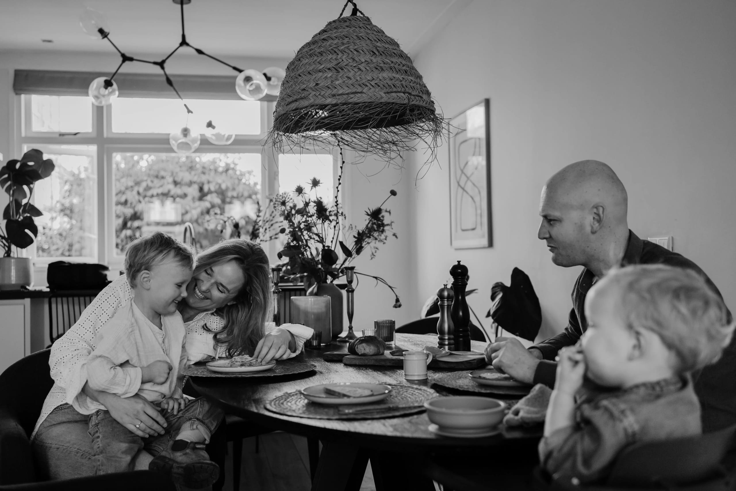 Zwart-wit foto van een gezin dat samen aan tafel zit, sfeervolle familiefotografie.