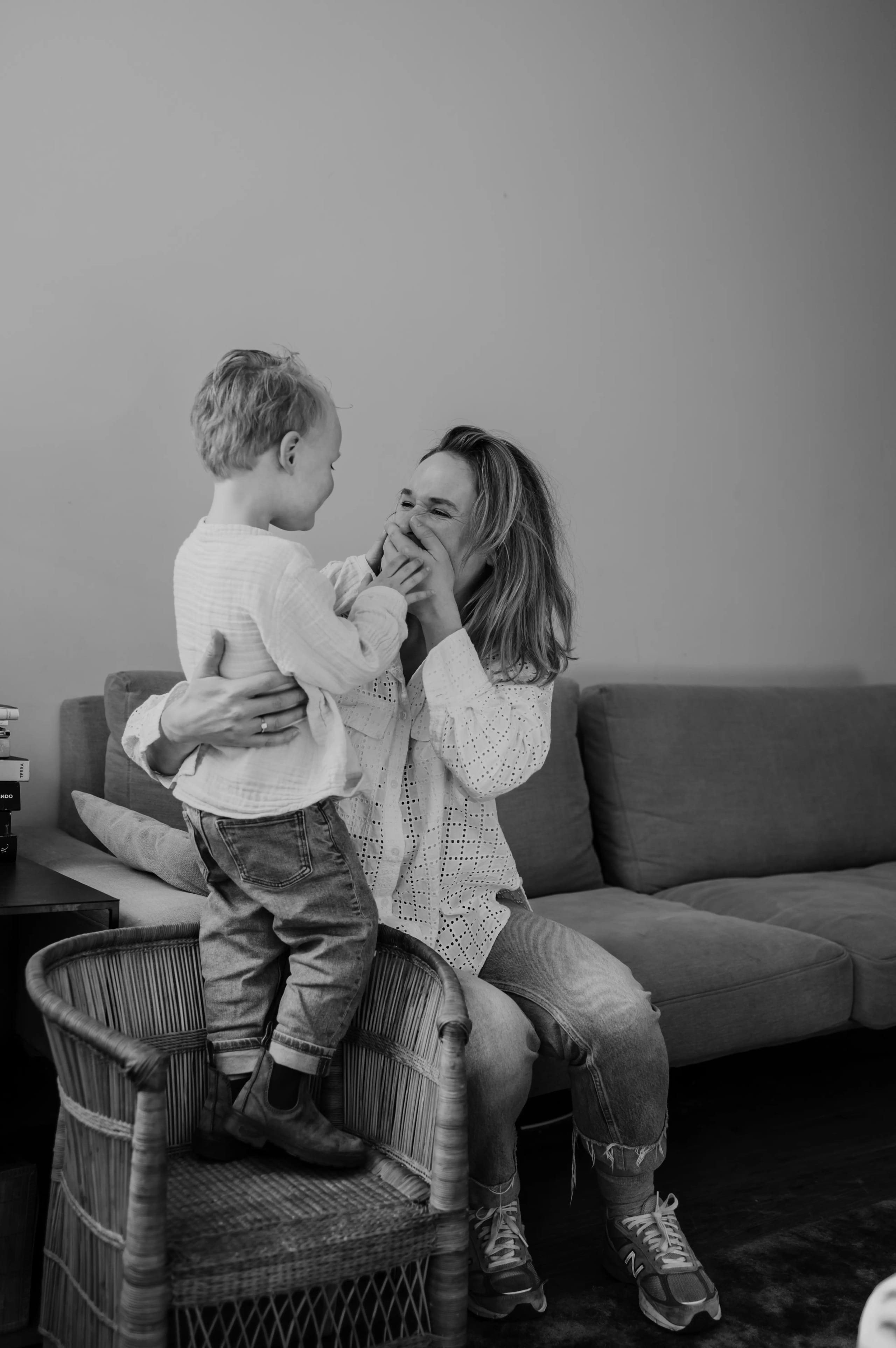 Moeder en kind knuffelen op de bank, intiem zwart-wit moment.