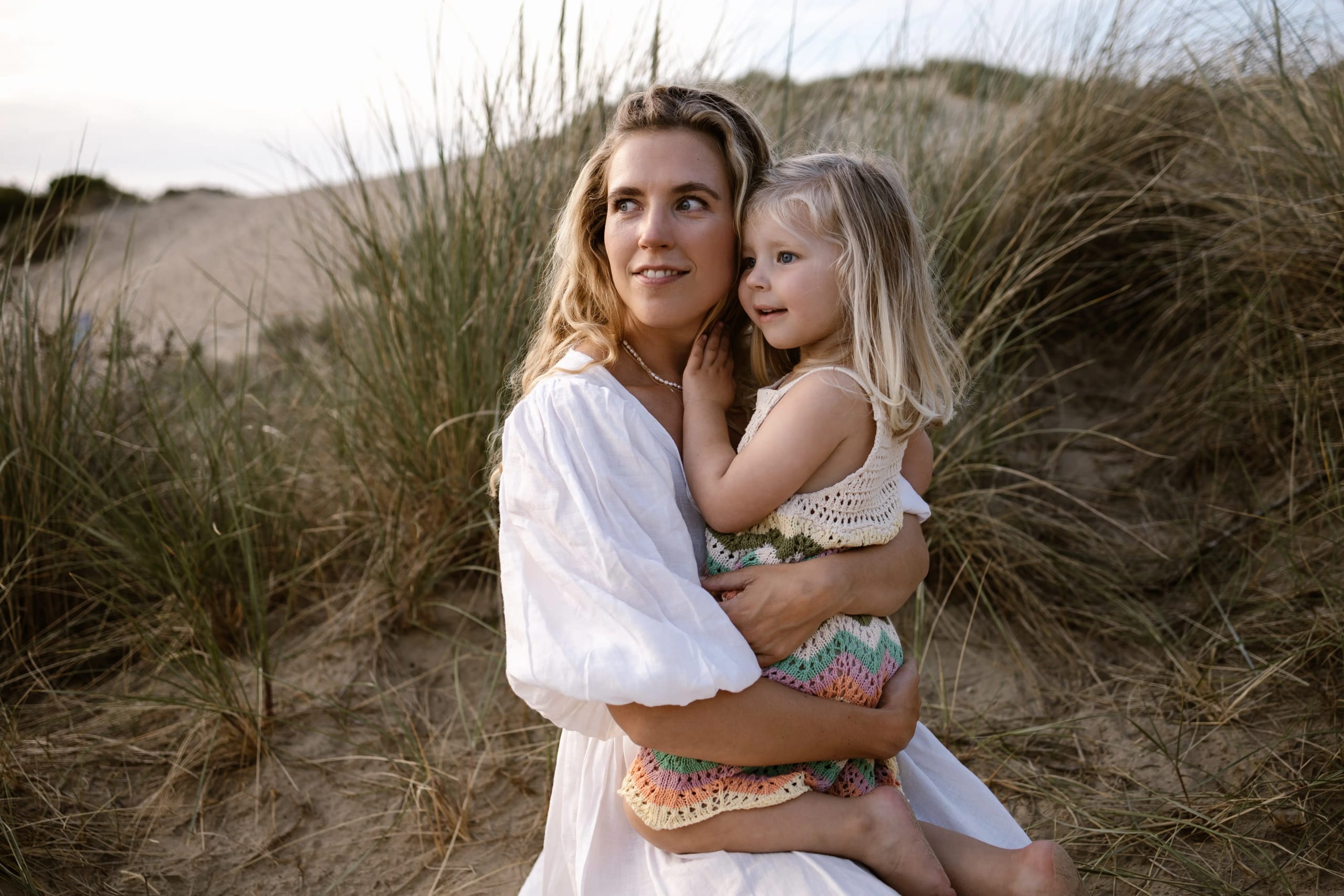 Liefdevol moment tussen moeder en kind in de duinen van Bloemendaal, lifestyle fotografie tijdens het gouden uur.