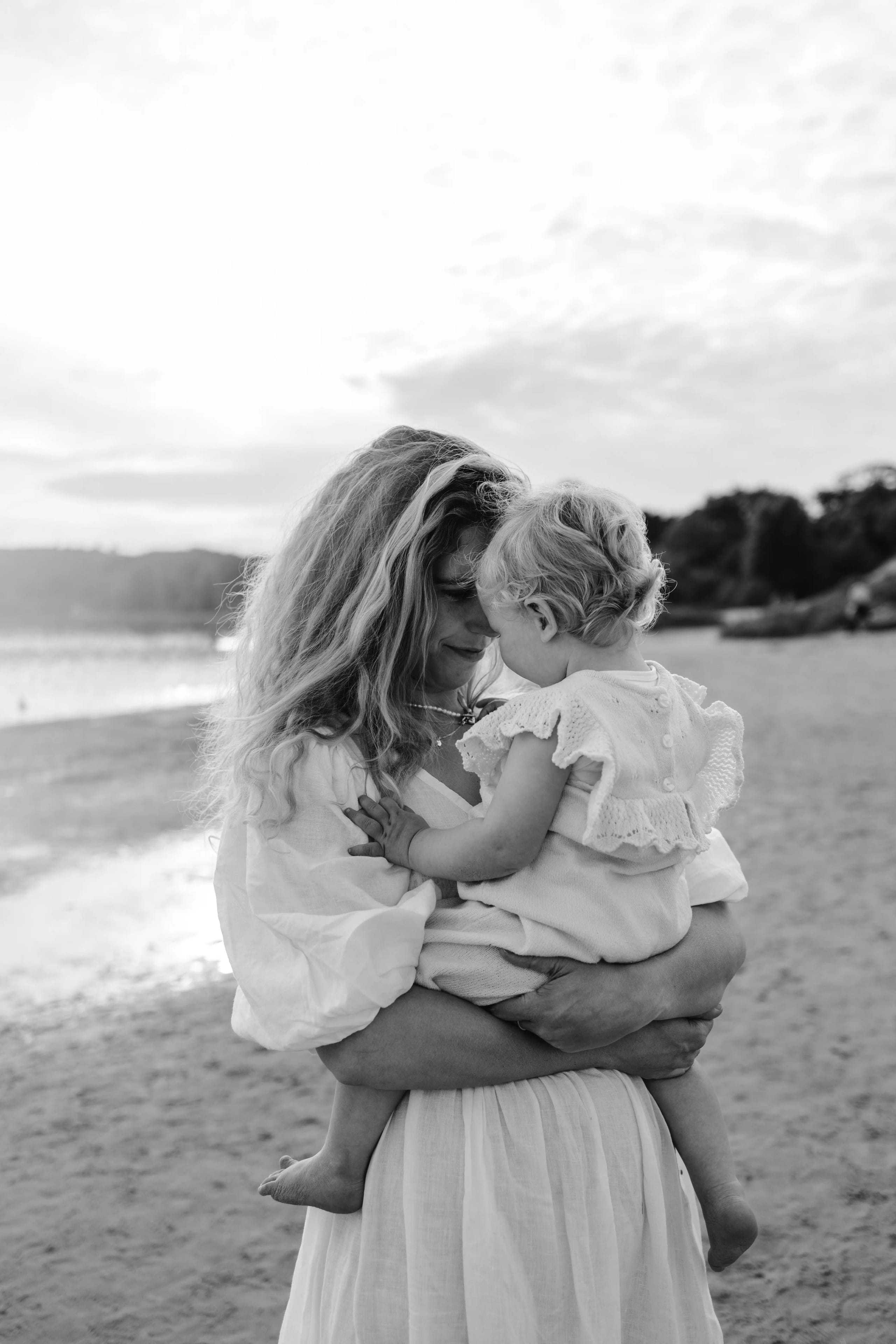 Zwart-wit detail van een kind dat veilig wordt gedragen op het strand bij Bloemendaal.