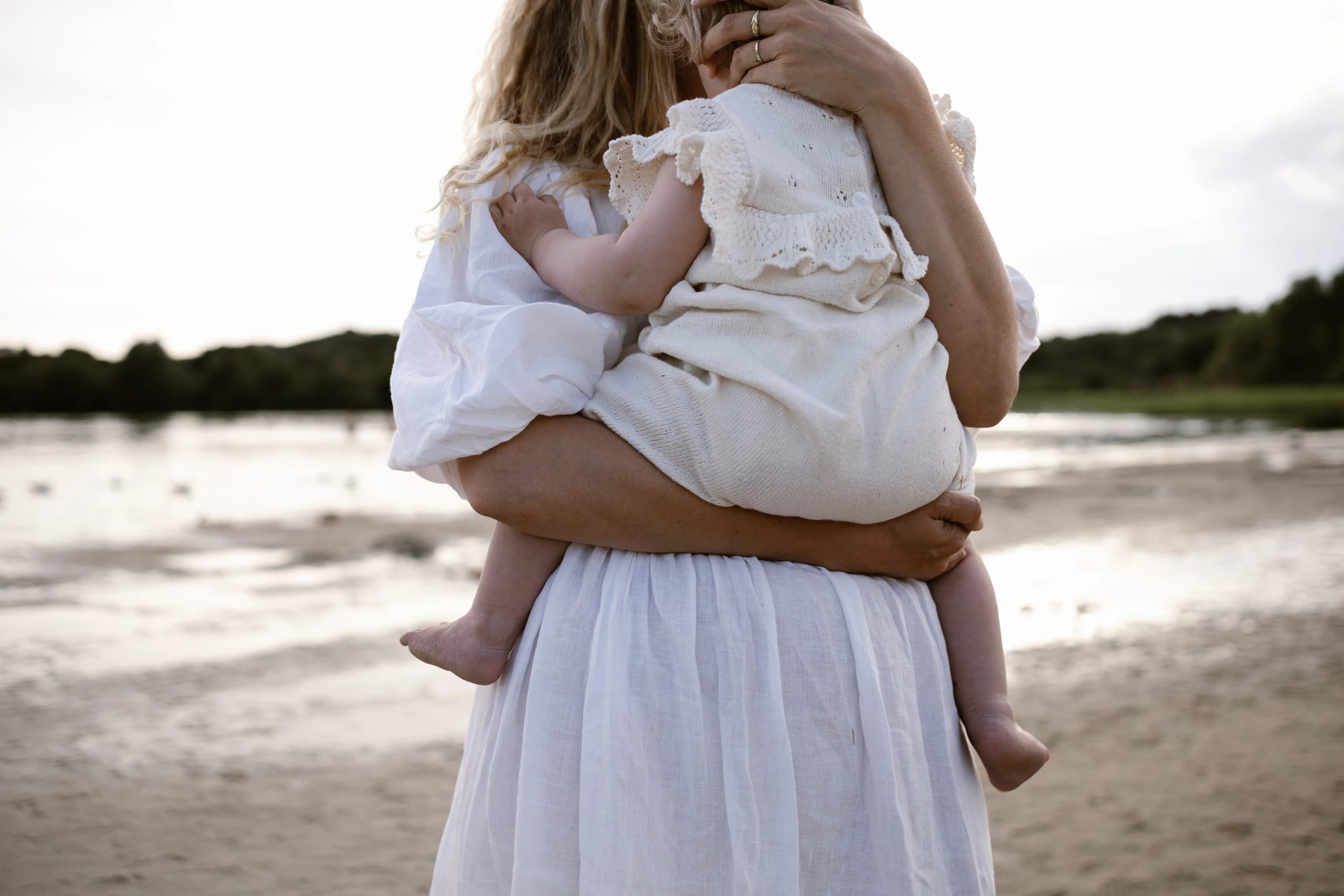 Moeder en kind in een innige omhelzing met de ondergaande zon in de haren bij Bloemendaal.