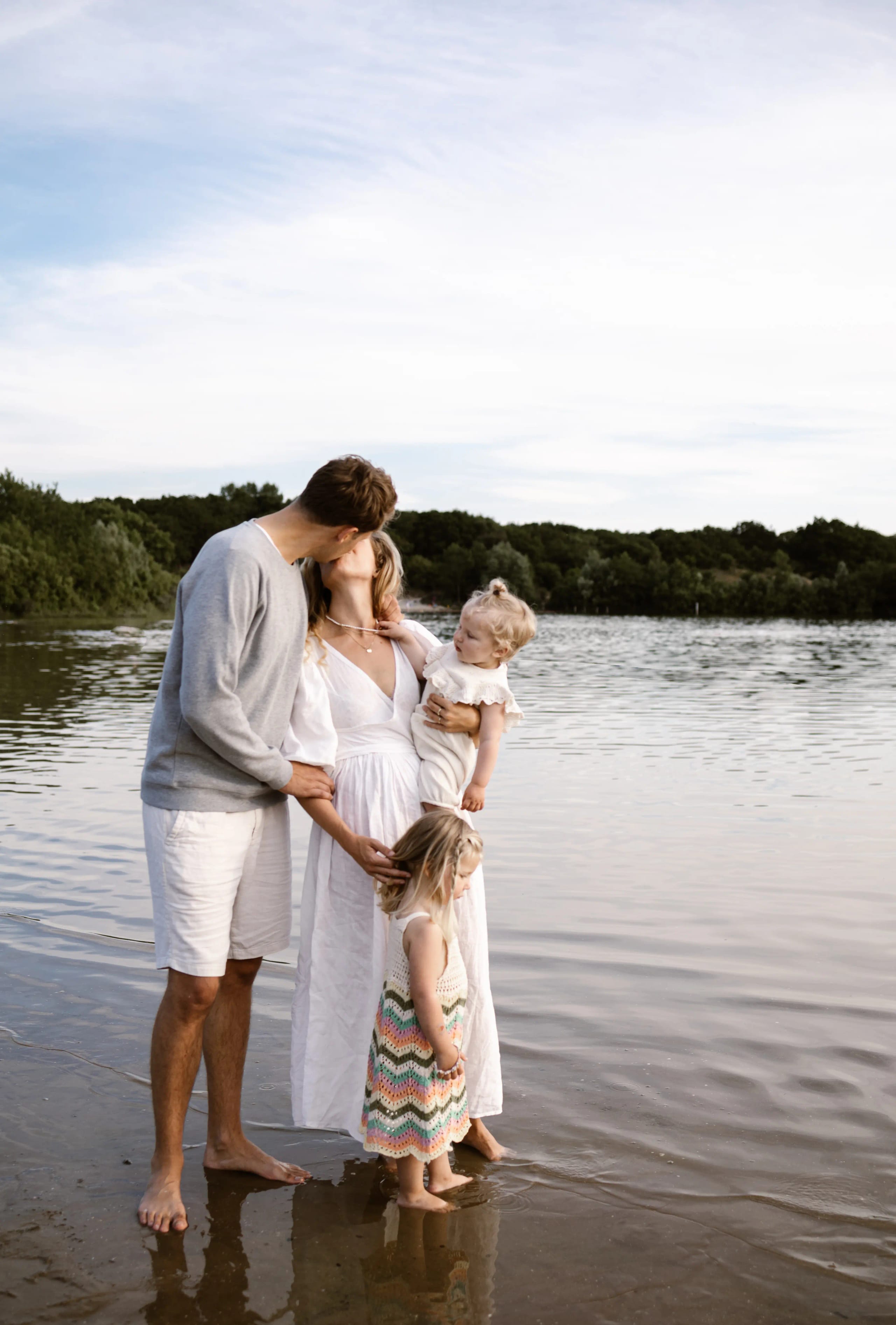 Liefdevolle blik tussen vader en moeder met hun kinderen in de duinen van Bloemendaal, romantische gezinsfoto.