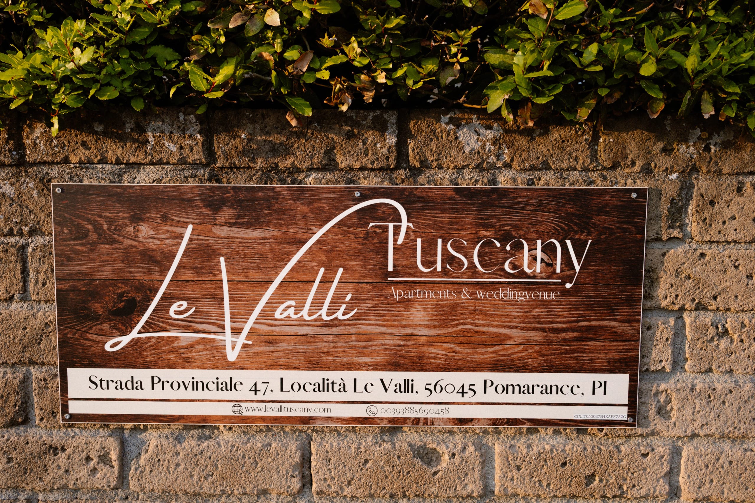 Houten bord met informatie over Le Valli, gelegen in Pomarance, Toscane, met details over appartementen en bruiloften.