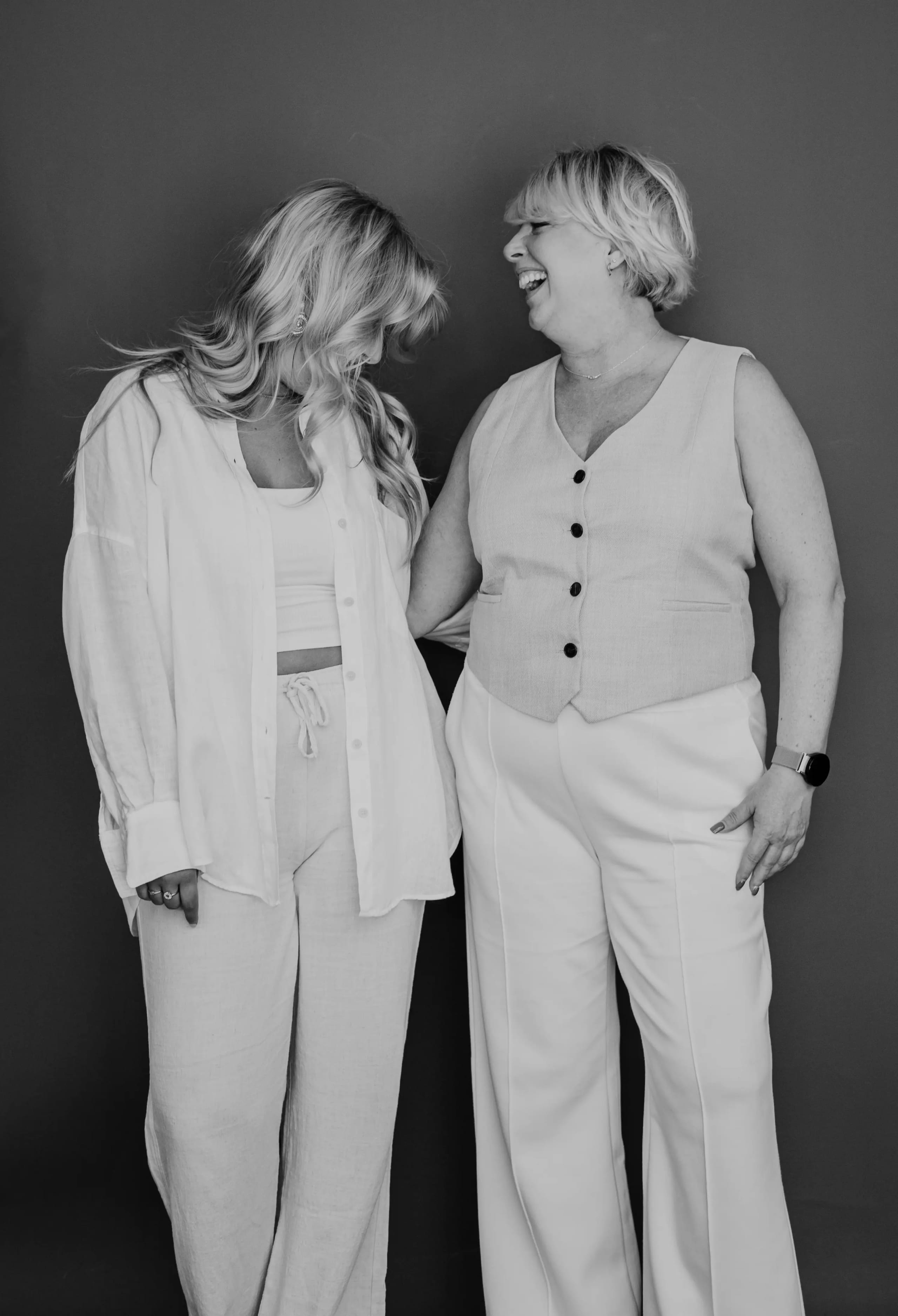 Zwart-wit foto van Joyce en Maica die samen lachen in witte kleding