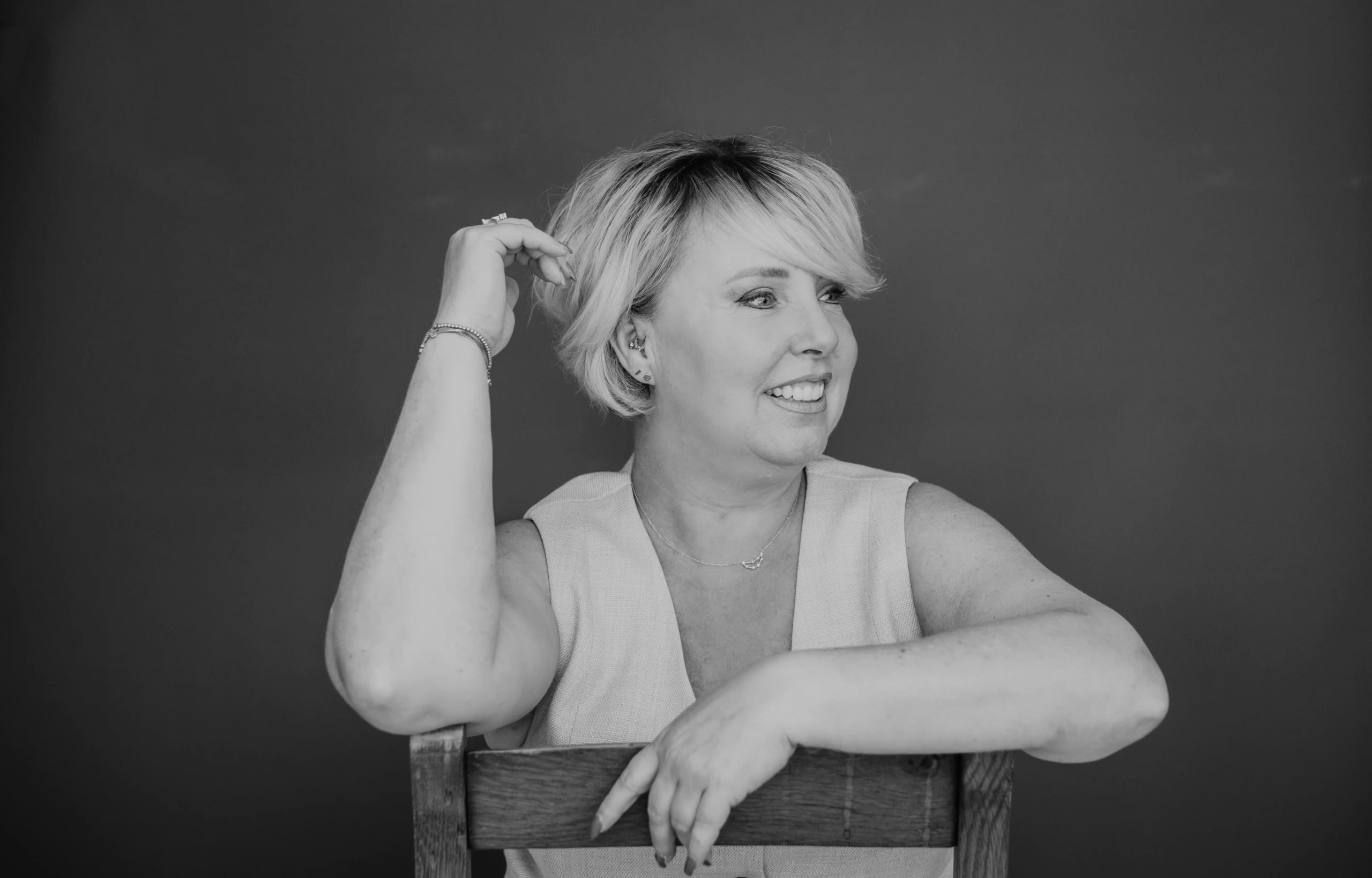 Maica kijkt lachend opzij met haar hand in haar haar, zwart-wit fotografie