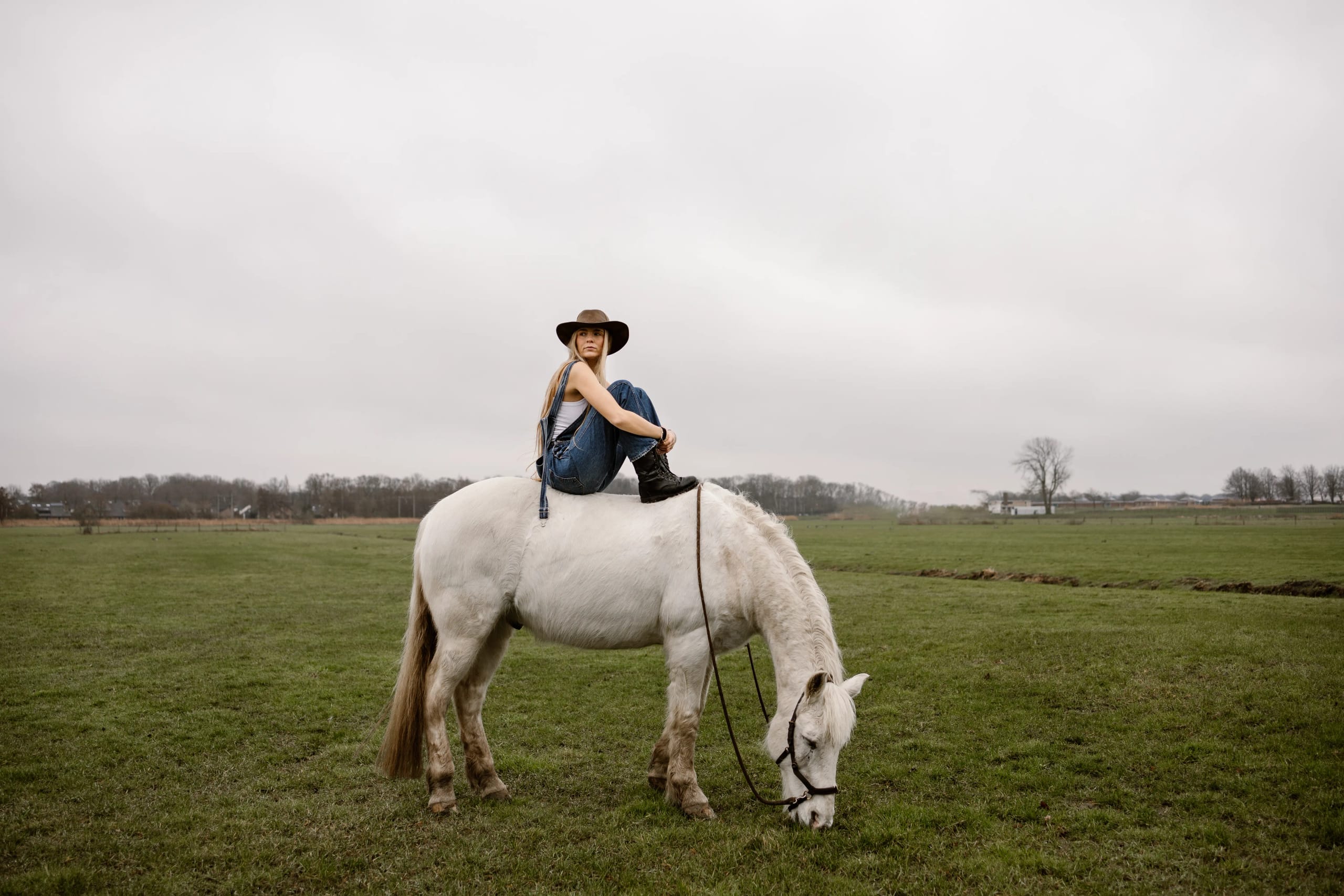 Lies Zhara zittend op een grazend wit paard in Hoofddorp