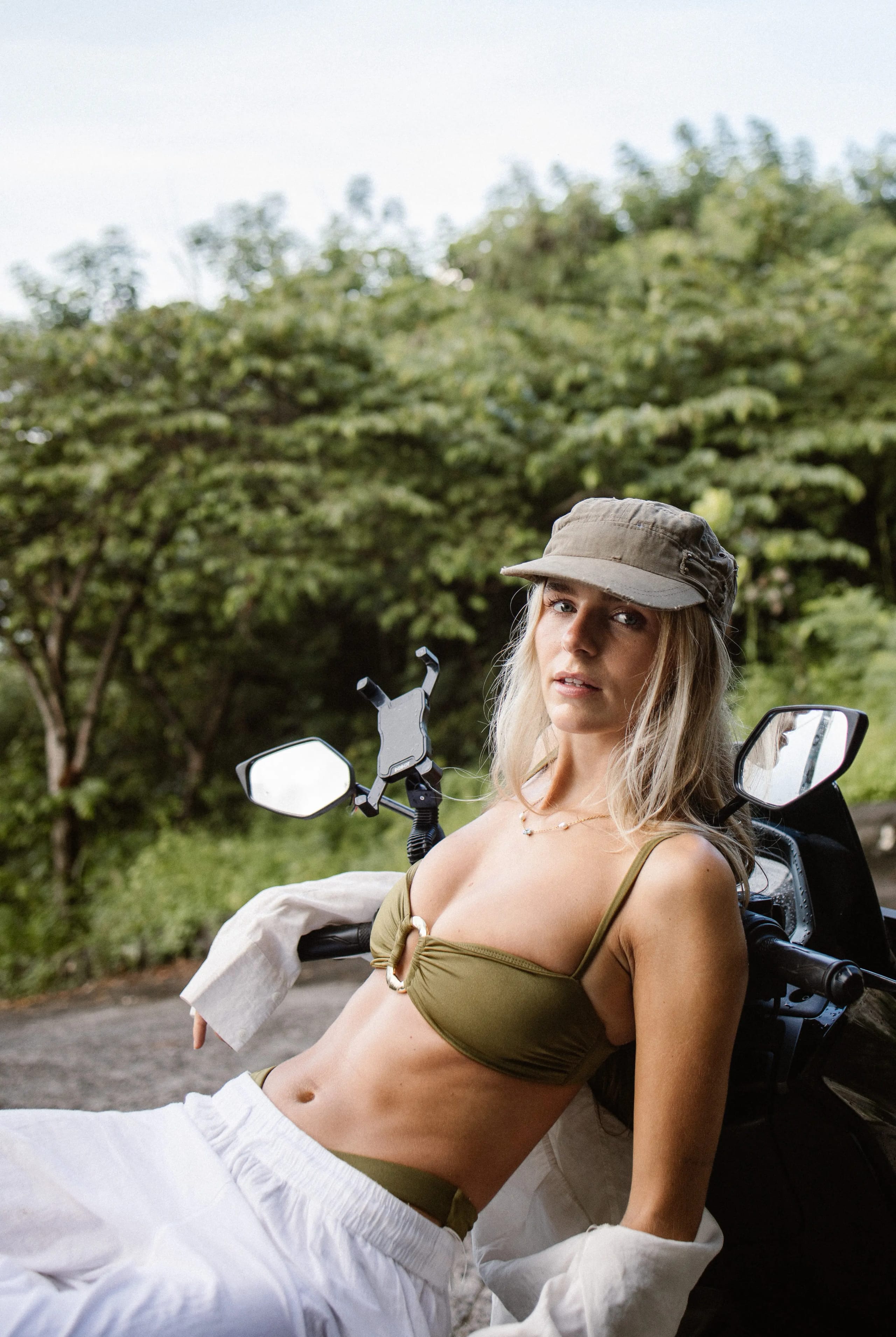 Lies Zhara zittend op een scooter in Bali met een legergroene pet