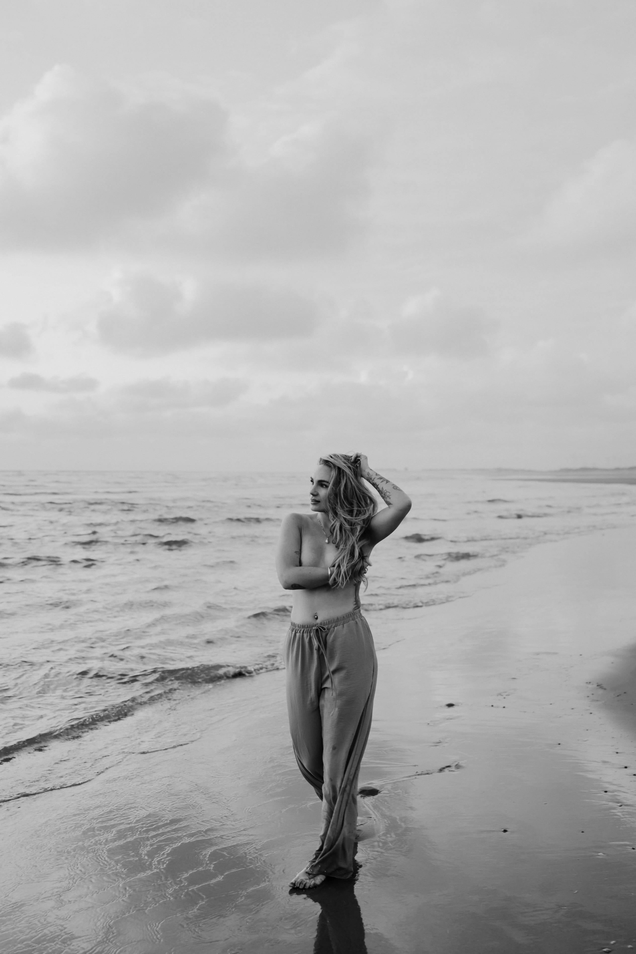 Zwart-wit opname van Sammy wandelend langs de zee voor een sensuele beach shoot