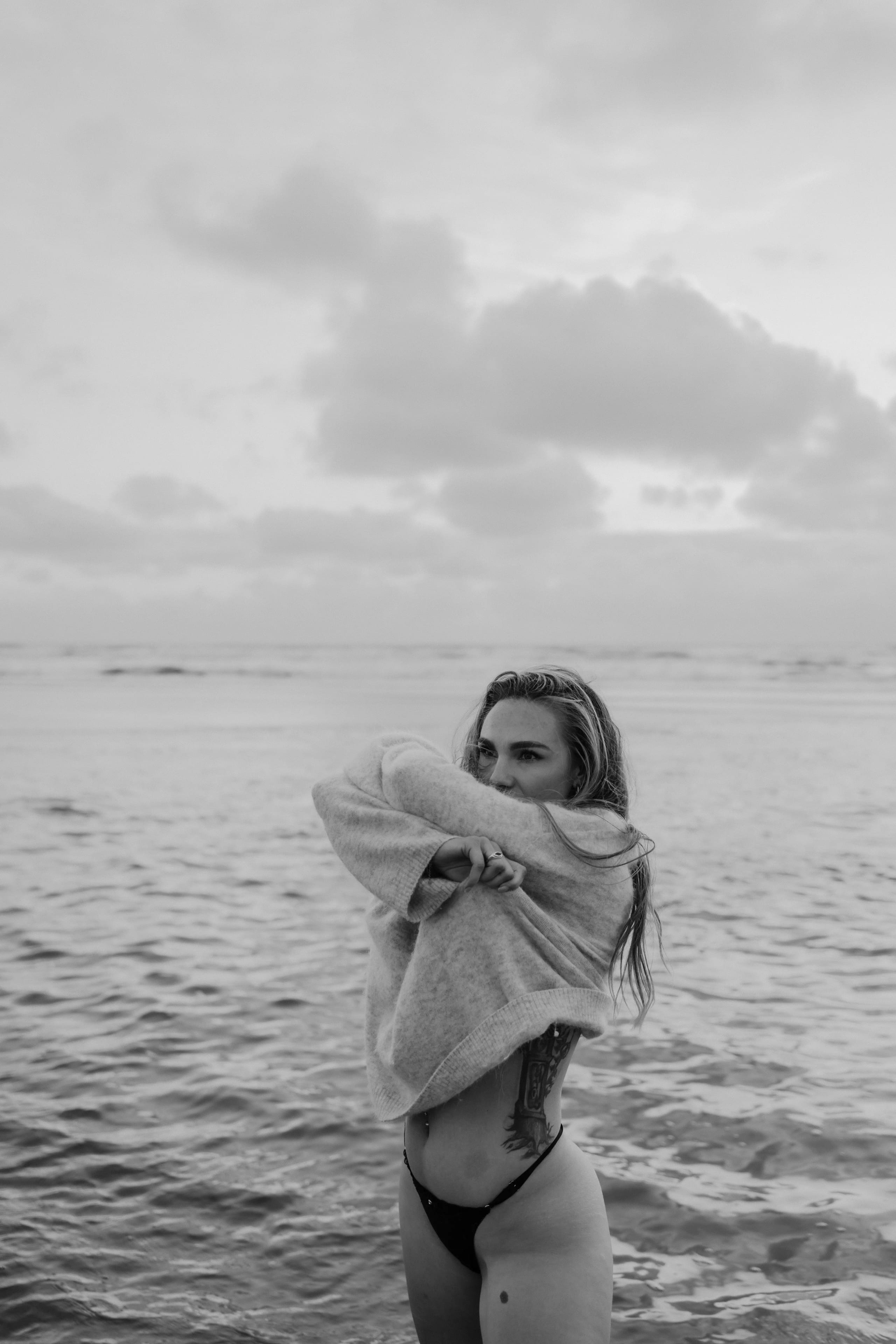 Zwart-wit artistieke boudoir opname van Sammy met een grijze trui in de Noordzee