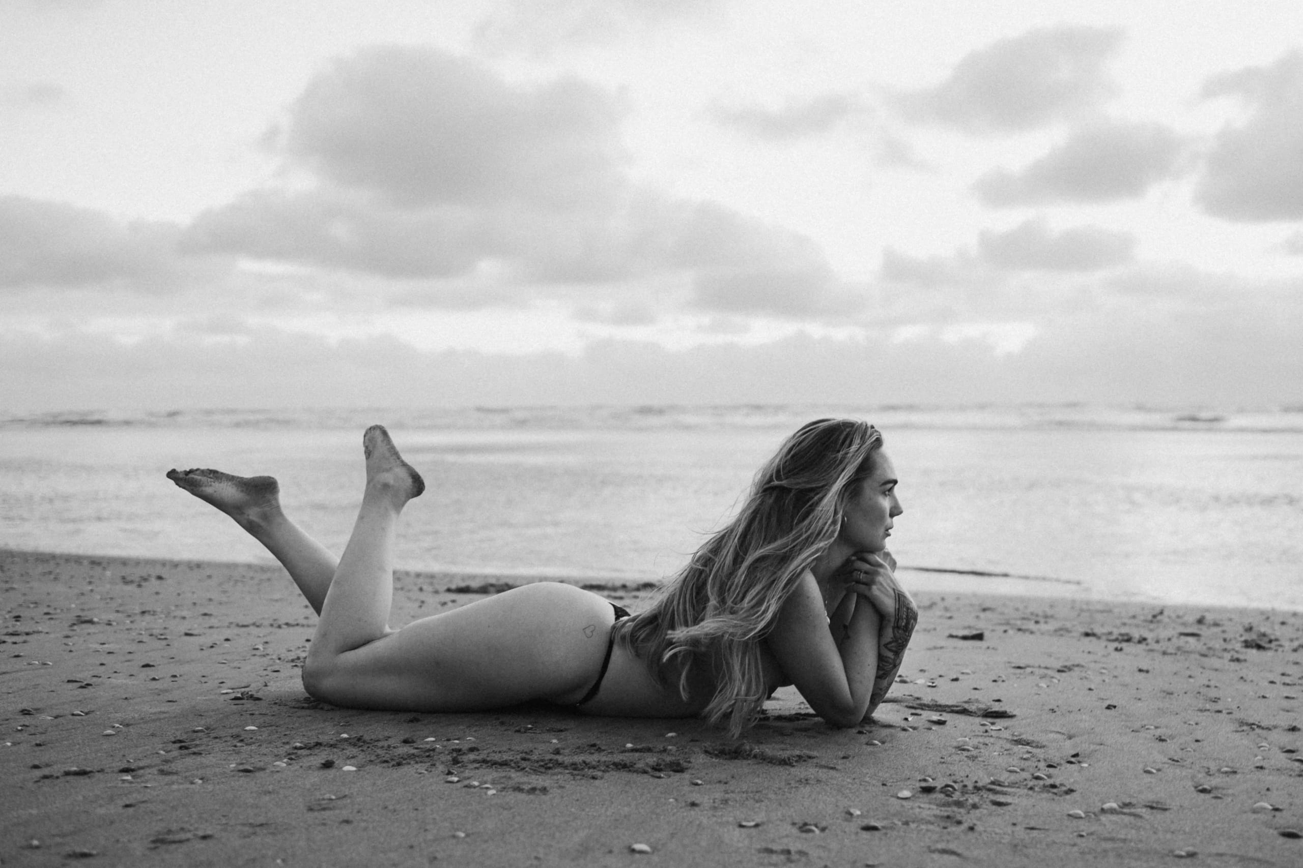 Artistiek zwart-wit boudoir portret van Sammy liggend op het strand van Bloemendaal